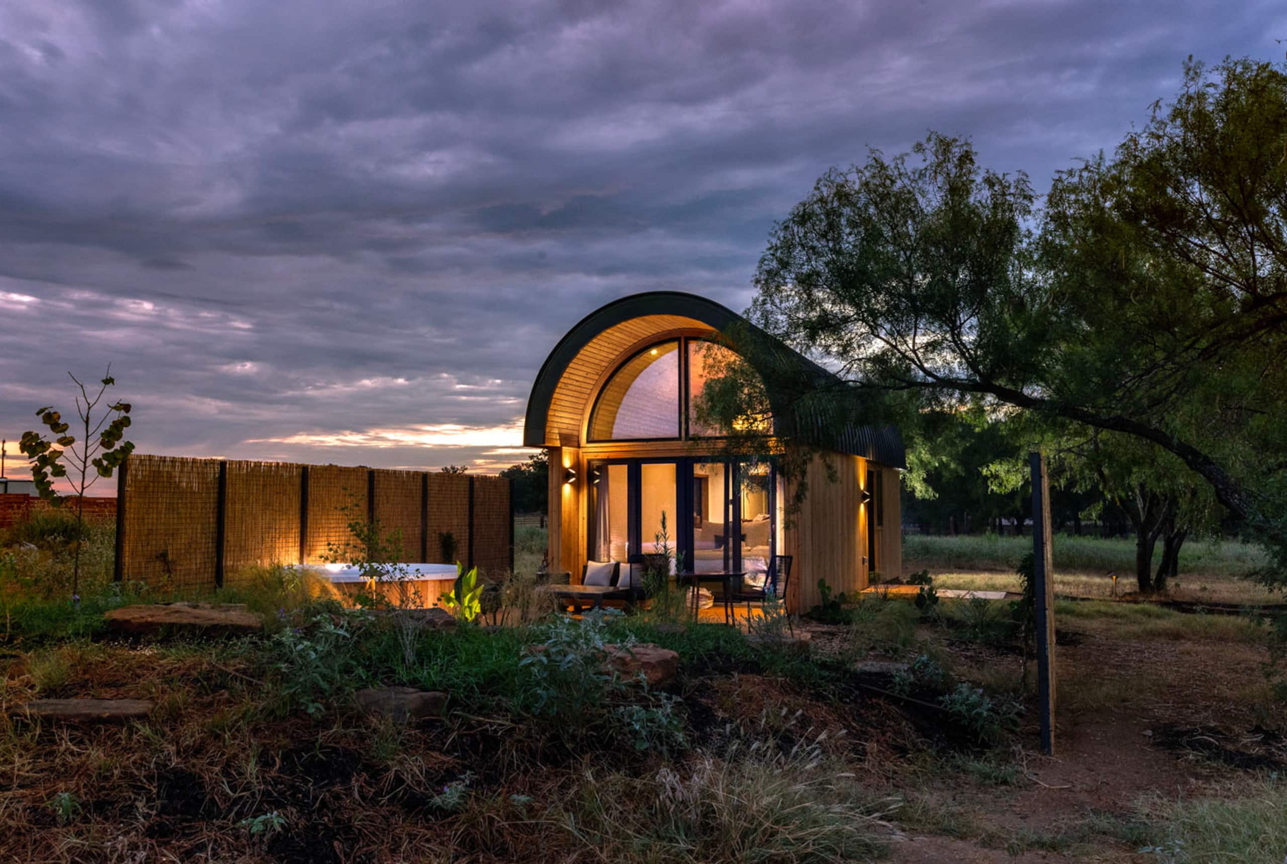 A Zenova villa glowing beneath a Hill Country storm sky at dusk